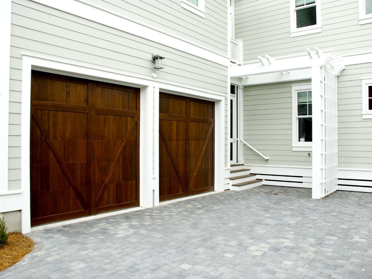 Pair of dark wood carriage doors on a grey-sided home